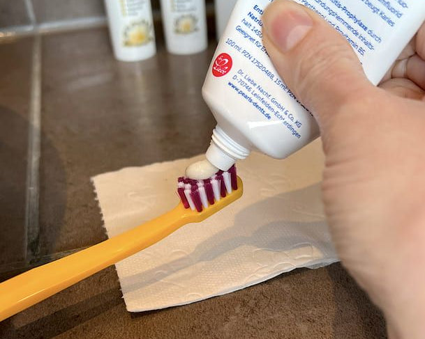 Anwendung von Propolis Tinktur beim Zähneputzen: Zahnpasta zuerst auf die Zahnbürste auftragen