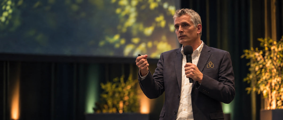 Dr. Wöll von Bienenherz -mit Mikrofon und Präsentationsfernbedienung auf einer Bühne.